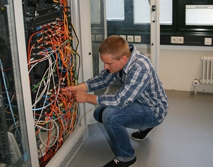Mann schließt an offenem Server Kabel an