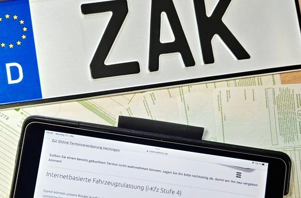 Ein Autokennzeichen mit der Aufschrift ZAK liegt vor einem Tablet