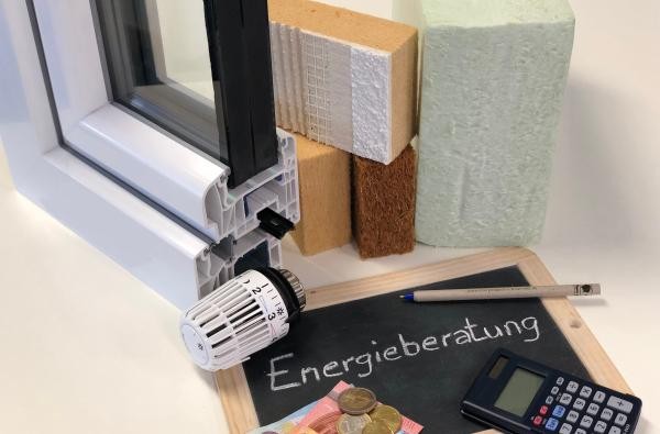 Auf einer Tafel steht "Energieberatung" daneben liegt Geld, ein Stift und Taschenrechner 