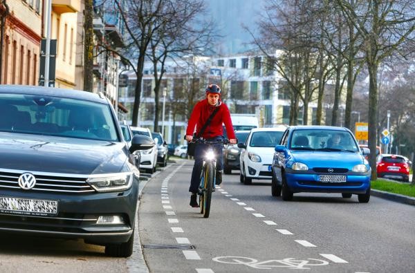 Ein Radfahrer auf einem Radfahrstreifen im Berufsverkehr zwischen Autos