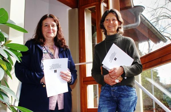 Zwei Frauen halten Dokumente in den Händen und lächeln