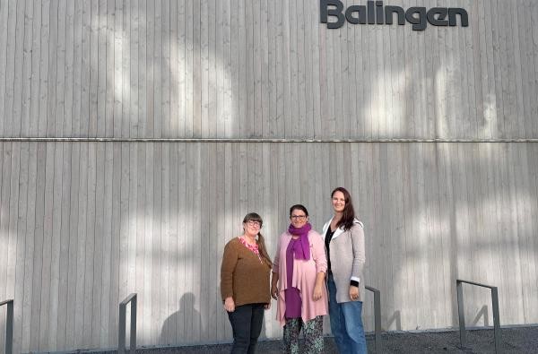 3 Frauen stehen nebeneinander vor einem grauen Gebäude 