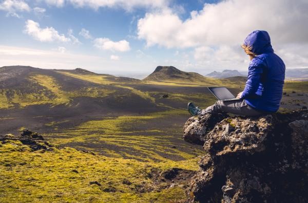 Woman sitting on a cliff with the laptop