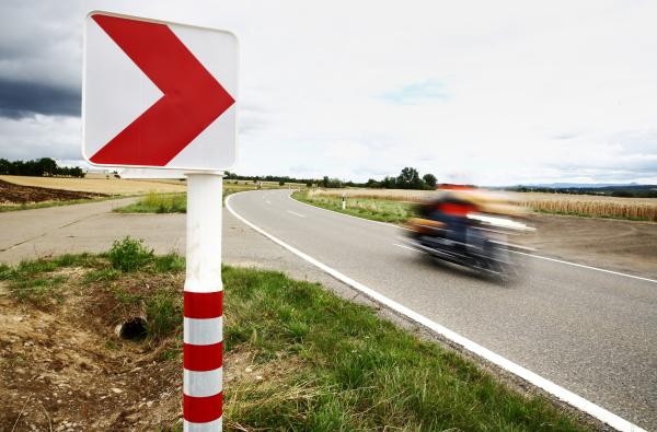 Das Bild zeigt einen Motorradfahrer, der an einer Kurvenleittafel vorbeifährt