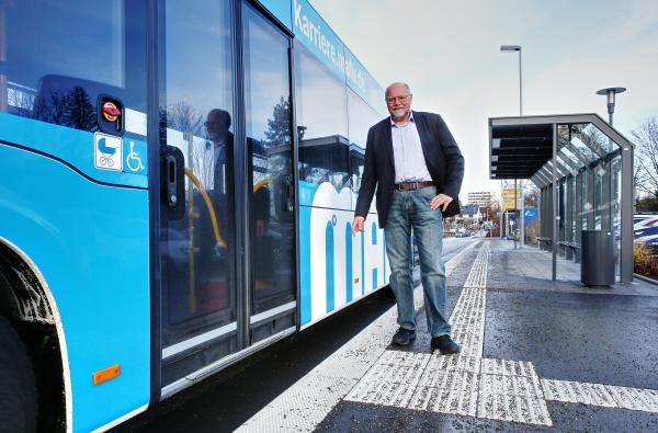 Ein Mann an einer Bushaltestelle, ein Bus steht dort