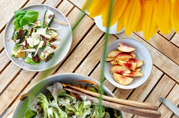 Ein einladend gedeckter Tisch mit leckeren Speisen. Der Hauswirtschafts-Beruf hat viele Facetten. ©Landratsamt Zollernalbkreis Auf einem Holztisch stehen Teller, eine Salatschüssel und eine Sonnenblume.