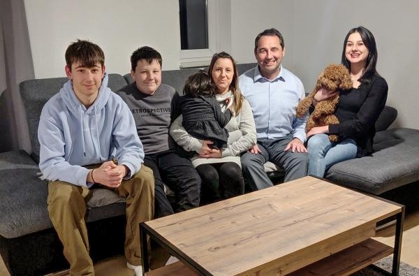 Familie Müller aus Ratshausen - Julia Müller hält Pflegekind Melli im Arm. ©Landratsamt Zollernalbkreis Eine Familie - zwei Erwachsene und vier Kinder - sitzen auf dem Sofa.