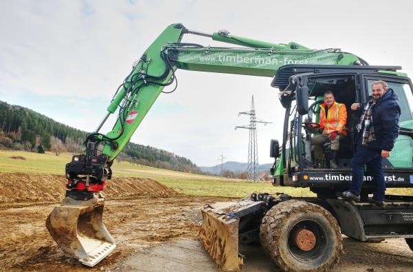 Landrat Günther-Martin Pauli (in der Baggerkabine) und Projektleiter Markus Riester begleiten den Start der Ausgleichsmaßnahmen auf dem Areal Firstäcker, wo das Zentralklinikum Zollernalbkreis entsteht. ©Landratsamt Zollernalbkreis Zwei Männer und ein Bagger.