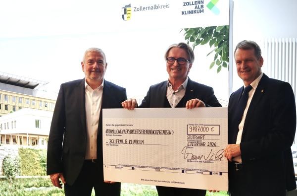 Dr. Gerhard Hinger, Vorsitzender Geschäftsführer des Zollernalb Klinikums, Minister Manne Lucha und Landrat Günther-Martin Pauli (von links) bei der Übergabe des symbolischen Förderschecks. ©Landratsamt Zollernalbkreis Drei Männer halten einen großen symbolischen Scheck in den Händen.