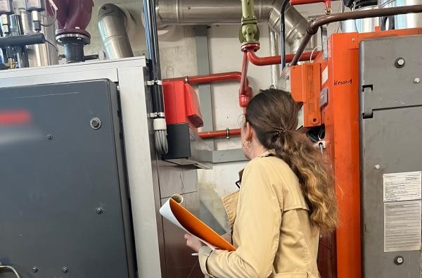 Genauer Blick: Heizanlagen in größeren Wohngebäuden müssen laut Gesetz überprüft werden. ©Energieagentur Zollernalb Eine Frau schaut sich eine Heizanlage an.