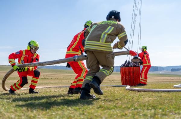Feuerwehrleute befüllen ein Bambi Bucket © Markus Voelter Photography http://photo.voelter.de Feuerwehrleute mit Stahlrohr befüllen Löschwasserbehälter