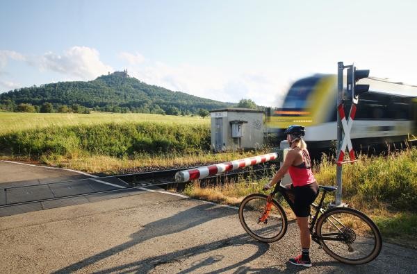Fleißig Rad-Kilometer gesammelt werden können beim Stadtradeln ab 21. Juni © Landratsamt Zollernalbkreis Eine Radfahrerin wartet an einem Bahnübergang bis ein Zug vorbeigefahren ist