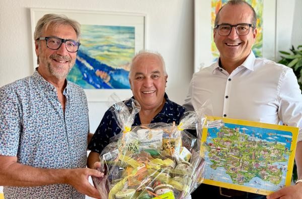 Sozialdezernent Georg Link (rechts) und Christoph Seisser (links) danken Eduard Maas für sein jahrzehntelanges Wirken in der Hospizarbeit.© Landratsamt Zollernalbkreis Drei Männer, der in der Mitte erhält zum Abschied einen Präsentkorb und das Wimmelpuzzle des Zollernalbkreises