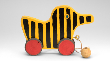 Bild: Tigerente gelb mit schwarzen vertikalen Streifen und zwei roten Rädern 